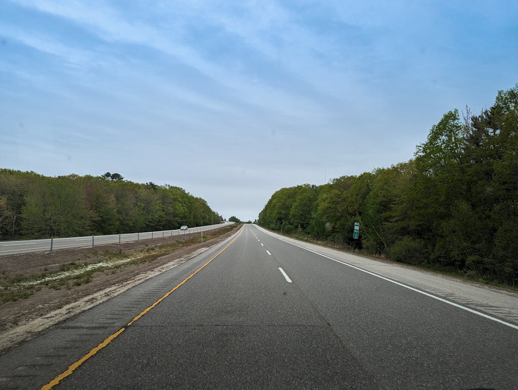 A scenic highway stretches through a lush forest in Maine during spring.